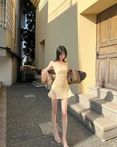 Ảnh mỹ nữ Trung Quốc mặc váy ngắn xếp ly đứng bên cửa sổ, ánh sáng tự nhiên chiếu vào làm nổi bật làn da trắng, tạo cảm giác vừa dễ thương vừa hấp dẫn