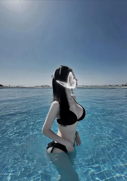 Cô nàng bikini bí ẩn ngồi trên cát lúc bình minh, nón rộng che kín mặt.