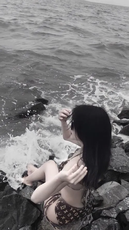 Bức ảnh đen trắng ghi lại cô gái ngồi sát mép nước, tóc dài che gò má, phần tay đặt hờ trên gối khiến dáng nghỉ ngơi trông mềm và kín
