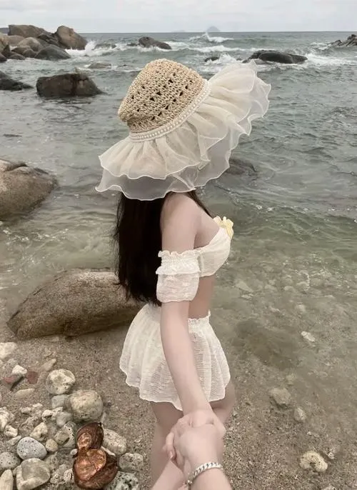 Từ góc nhìn trên cao, cô nàng lội qua làn nước nông với váy trắng bèo lớn và mũ cói, toàn khung gợi cảm giác du lịch hè rất thư thái