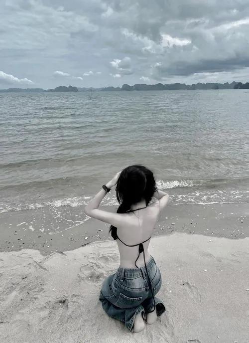 Khung đen trắng bắt lấy khoảnh khắc cô gái quỳ trước sóng với hai tay giơ cao, mái tóc ôm lưng giúp quý cô quyến rũ dưới nắng hè hiện lên rất thoáng