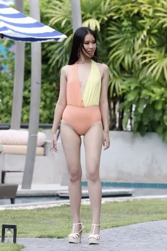 Cô nàng đứng trong hồ nước nông, mặc áo tắm một mảnh màu xanh đậm, nước ngang đùi tạo cảm giác mát lạnh