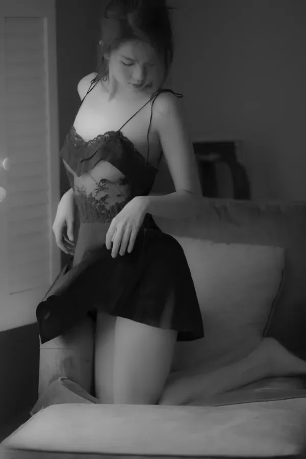 Người mẫu nằm nghiêng bên phải một tay vuốt tóc, ánh mắt mơ màng và đường cong tổng thể hiện rõ dưới đèn dịu.