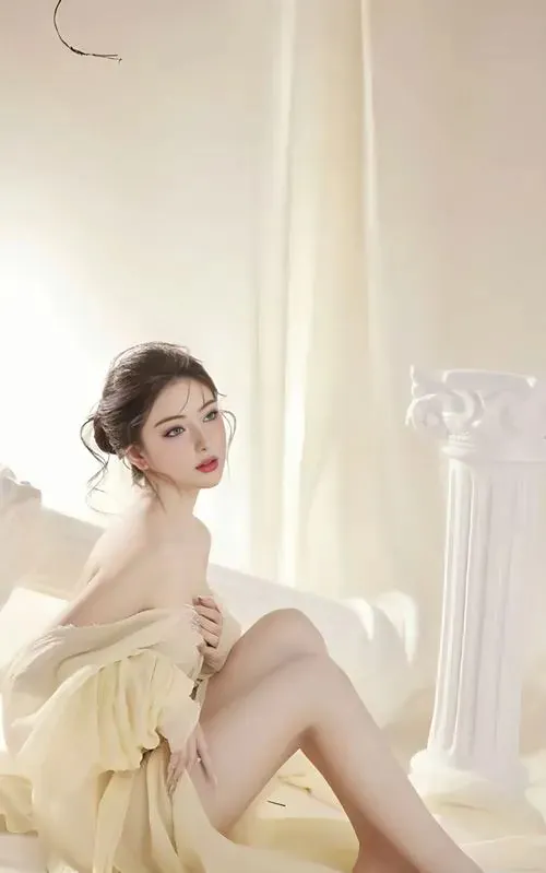 Gái xinh trong tư thế ngồi ôm gối, ánh mắt hướng thẳng ống kính với nụ cười nhẹ nhàng ấm áp.