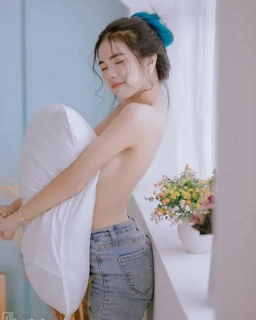 Người mẫu nằm sấp quay mặt nghiêng, bả vai tròn trịa và ánh sáng từ bên tạo đổ bóng tinh tế.