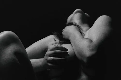 Người mẫu đứng quay lưng tựa cửa sổ, tay nâng tóc để lộ bờ vai tròn và làn da sáng mịn trong bóng chiều dịu.