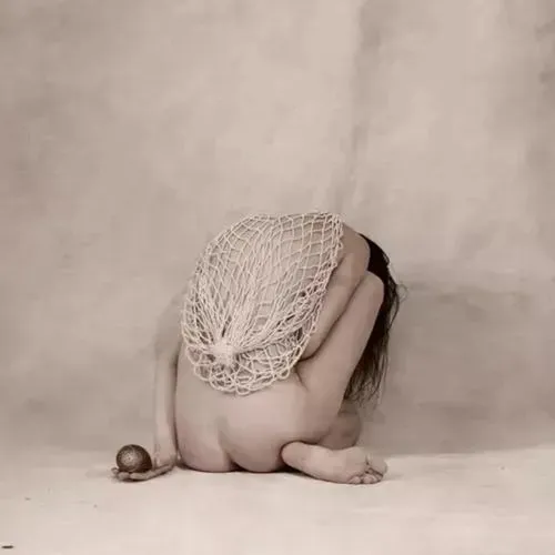 Người mẫu nghiêng người ôm cột trụ, ánh sáng chiếu nghiêng tạo tương phản trên da và đường nét uyển chuyển của hông.