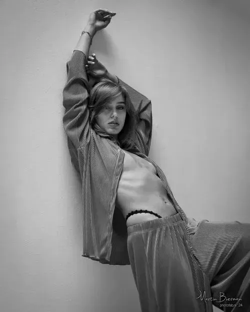 Thiếu nữ quỳ gối trên sàn, lưng cong mềm mại và mái tóc dài buông xuống che phần ngực trong ánh sáng vàng ấm.