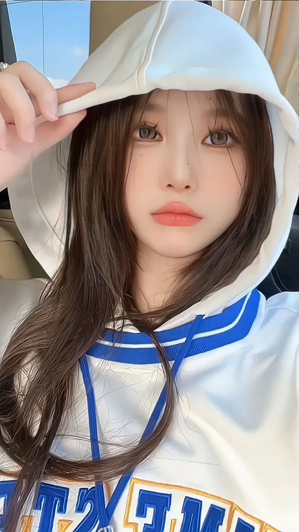 Cô gái đội mũ hoodie trắng xanh nhìn chếch lên máy ảnh, môi hồng nhạt và làn da sáng giúp bức chân dung mang sắc thái trong veo đầy nữ tính