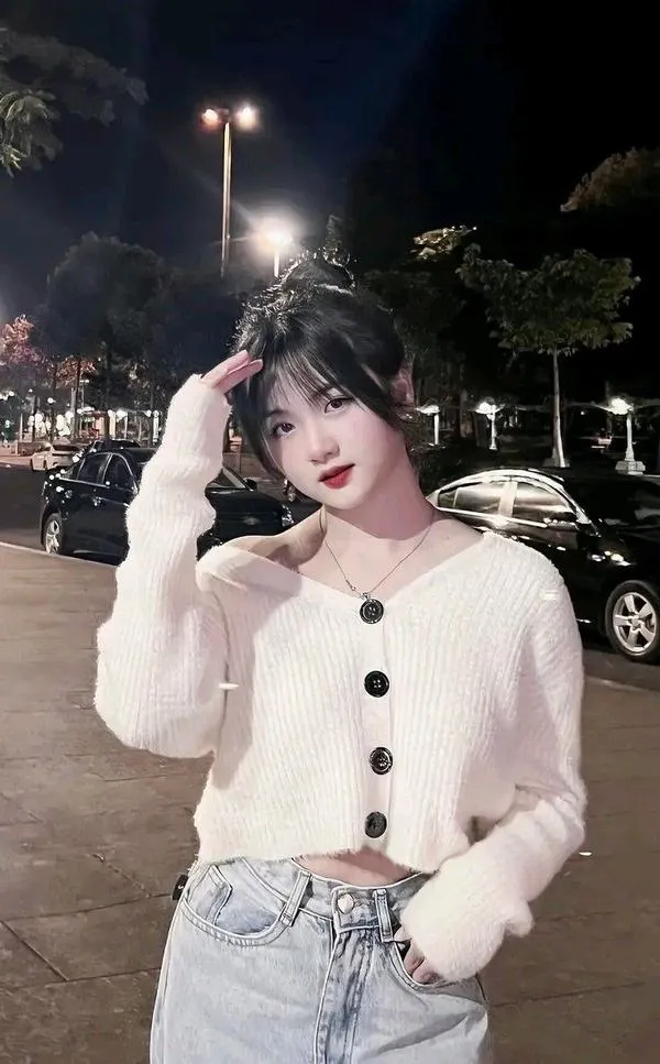 Mỹ nữ Trung Quốc tạo dáng chữ V trên phố đêm, áo cardigan trắng phối váy hoa xám và nụ cười nhỏ làm không khí trở nên tươi tắn