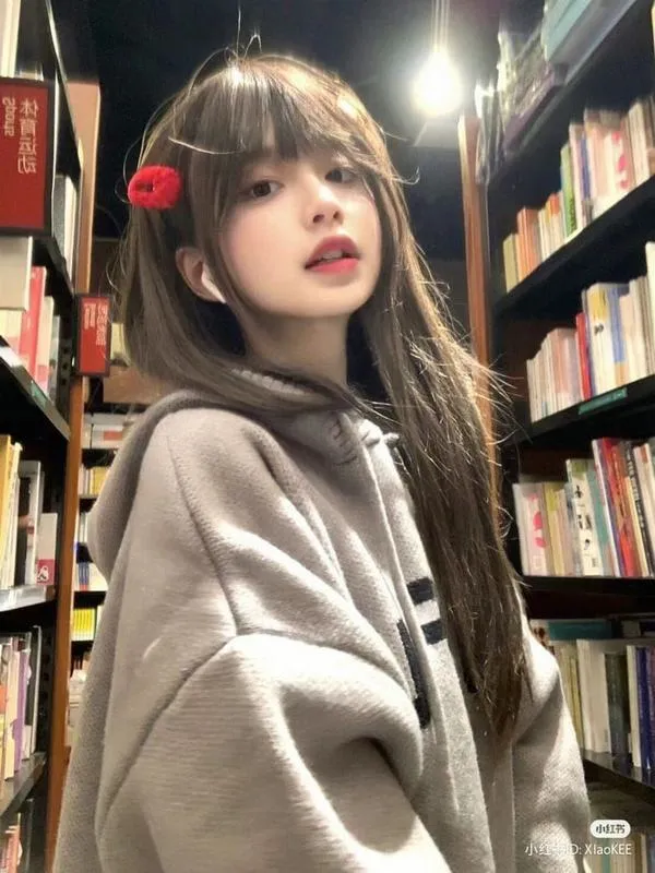 Trong hiệu sách, cô nàng khoác áo nỉ be, tóc mái dày và gương mặt nghiêng lên ánh đèn khiến bức chân dung có nét ấm áp rất dễ chịu