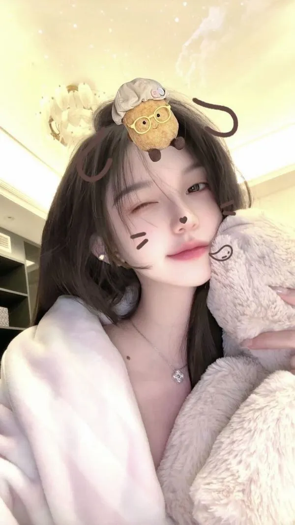 Cô gái ngồi trên ghế da ở studio, diện sơ mi satin tím đậm và son đỏ mận, cách bắt chéo chân làm tổng thể trở nên sang mà gọn