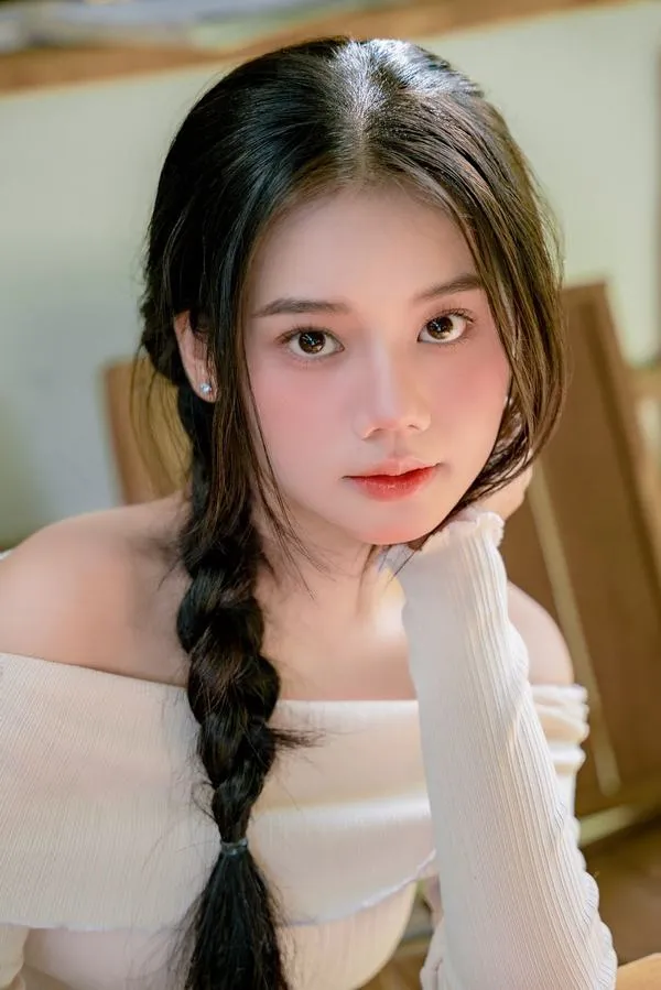 Bím tóc đôi và chiếc áo trắng đơn giản khiến cô nàng tựa cằm nhìn máy ảnh trông hiền hòa, nền sáng mờ càng làm gương mặt thêm trong