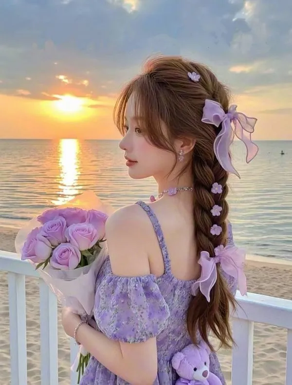 Gái xinh Trung Quốc mặc váy tím cầm bó hoa bên bờ biển lúc hoàng hôn, quay nghiêng nhẹ để mái tóc tết hiện ra rất bay bổng