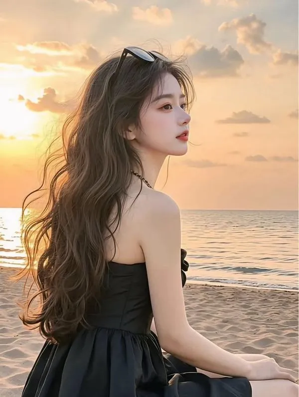 Chiếc váy đen hở lưng và nắng vàng cuối ngày làm cô gái ngồi xoay nửa người trên cát trở nên lôi cuốn mà vẫn mềm mắt