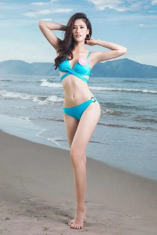 Hình chụp cô gái trên bãi biển trong bikini xanh ngọc, hai tay đưa ra sau đầu và một chân bước nhẹ khiến dáng đứng rất thoáng mắt