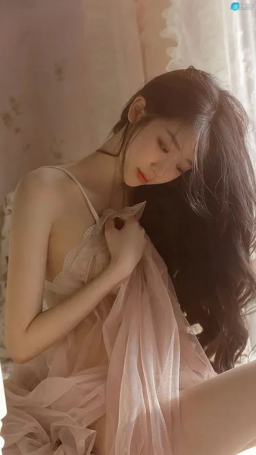 Người mẫu nằm nghiêng co gối, một tay chống đầu và mái tóc dài rơi xuống vai mượt mà.