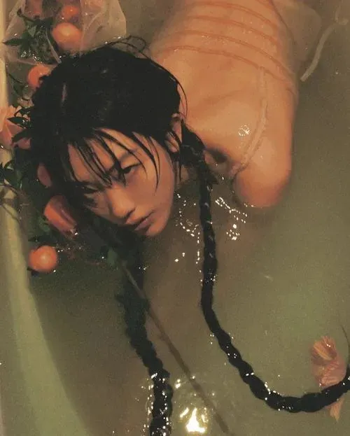 Thiếu nữ quỳ với lưng cong, ánh mắt nhìn xuống và không khí yên bình bao quanh.