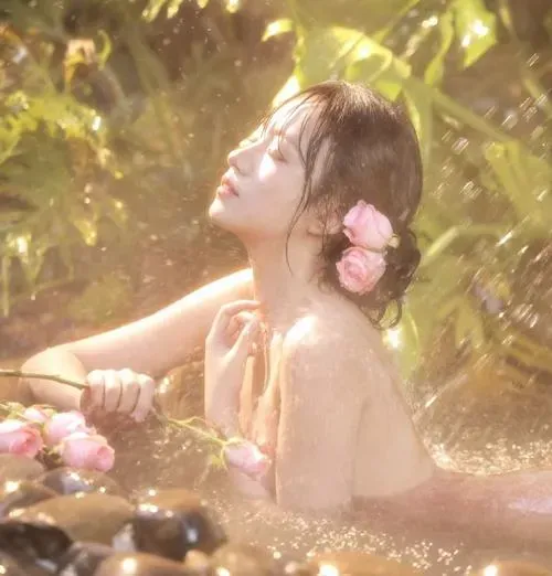 Nàng ngồi co người ôm chân, biểu cảm mơ màng và da sáng dưới đèn studio.