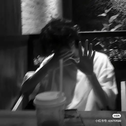 Hình avt chàng trai cúi đầu giữa khung đen trắng, tay kéo khăn hoặc áo lên che mặt, lớp hạt ảnh làm tổng thể ngầu và hơi gai góc