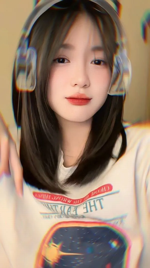 Trong căn phòng treo đầy ảnh film, nàng cầm máy compact bạc áp lên má, tóc xoăn ngắn và biểu cảm tinh nghịch làm cả góc tường sáng hẳn