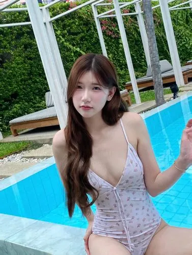 Hình nền điện thoại thiếu nữ đứng bên hồ bơi, mặc bikini một mảnh màu xanh, tay chạm nhẹ lan can, ánh nước phản chiếu làm ảnh thêm sinh động