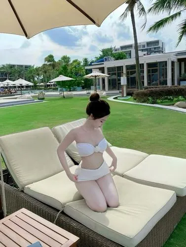 Ảnh bìa người mẫu nằm ngửa giữa hồ bơi, tay dang nhẹ, bộ bikini trắng nổi bật trên nền nước xanh trong và ánh nắng chiếu thẳng