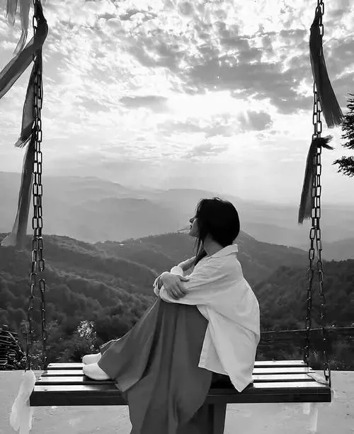 Avatar nữ cô đơn cô gái ngồi trên xích đu nhìn ra dãy núi xa, khăn choàng sáng phủ vai và lưng quay máy ảnh tạo cảm giác một mình