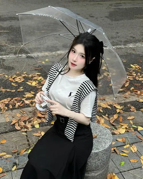 Thiếu nữ Việt trong tà áo dài trắng thướt tha đứng bên hồ sen, mái tóc đen mượt mà tạo nên một vẻ đẹp thanh thuần đậm chất truyền thống