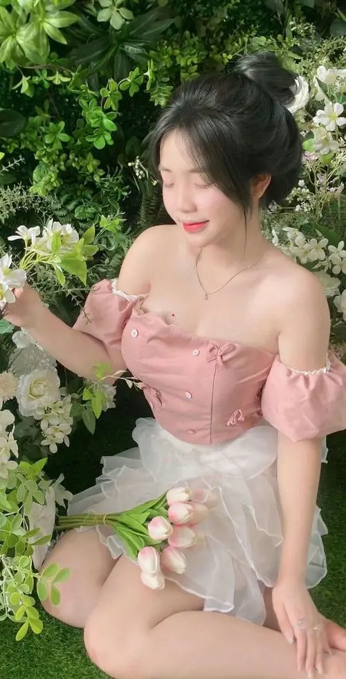 Trên thảm cỏ xanh mướt, nàng thiếu nữ nằm nghiêng đọc sách với vẻ mặt chăm chú, mái tóc dài trải rộng tôn lên sự thanh tú đầy cuốn hút