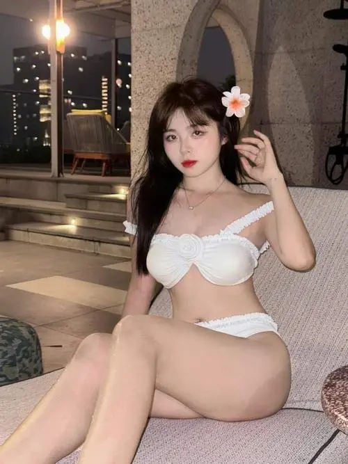 Gái biển dáng thon bước sát mép sóng với bikini màu da, đầu cúi nhẹ và tóc rủ về trước ngực tạo cảm giác mềm và khá cuốn mắt