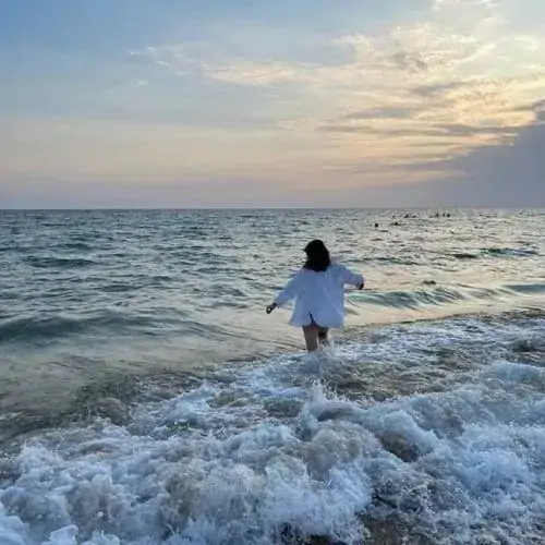 Cô nàng trong áo khoác jean tựa lưng vào máy giặt ở tiệm giặt tự động tóc buộc cao để lộ cổ áo nhìn hiện đại mà không phô