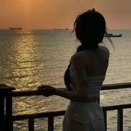 Bạn nữ diện váy dài màu rêu đứng dưới mái che bến phà nhìn mặt nước xám đục và sợi dây buộc tàu kéo khung hình theo hướng rất lạ