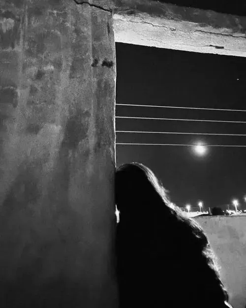 Người con gái ngồi trên nắp capo chiếc xe cũ ngoài gara, mái tóc buộc thấp và bàn tay dính bụi mỡ làm vẻ lặng im càng sát đời thường