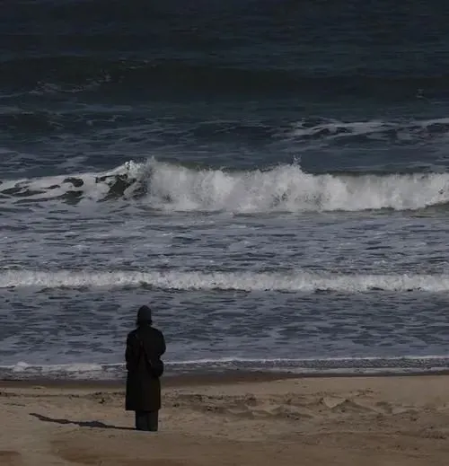 Thiếu nữ ngồi ở vòng quay ngựa gỗ đã tắt đèn, váy nhạt phủ qua gối và nền công viên vắng khiến niềm vui cũ như rơi mất