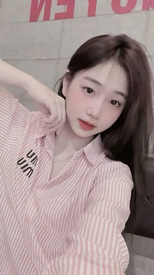 Mỹ nhân đang cầm bó hoa tulip nhỏ đứng giữa cánh đồng, áo babydoll be, tóc búi lỏng, ánh mắt trong veo đầy nữ tính.