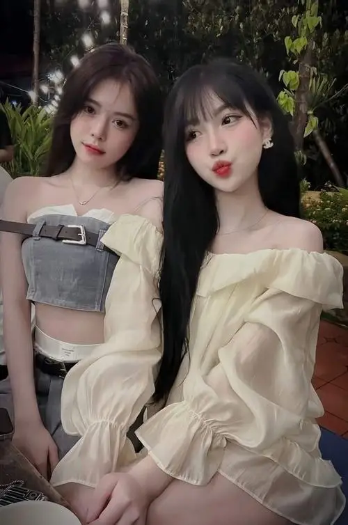 Cô bé đang đứng nghiêng người bên bức tường trắng studio, mặc áo thun crop và short, tóc xõa nhẹ, mắt to tròn long lanh duyên dáng.