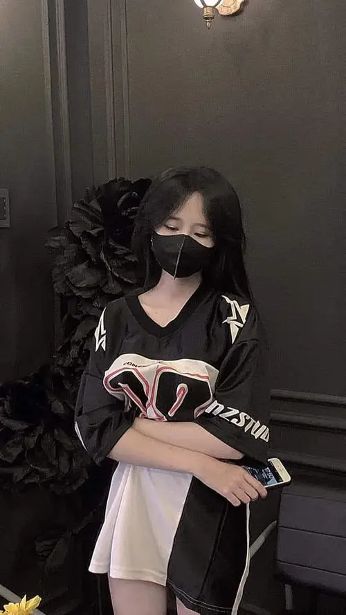 Cô đang quay lưng nhẹ nhìn hoa rơi, váy voan dài, tóc dài óng ả, biểu cảm mơ màng đầy thanh xuân dưới ánh chiều.