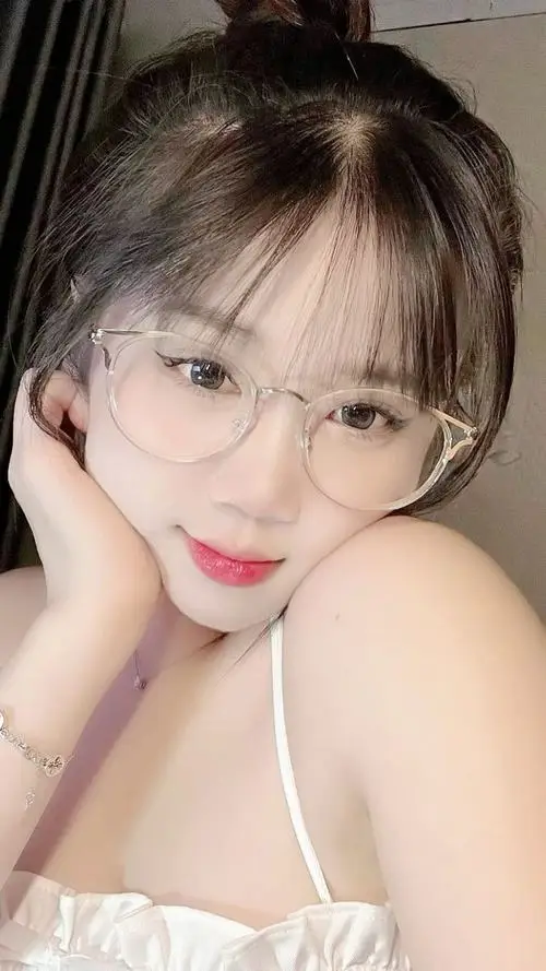 Cô bé đang cầm ly trà sữa lớn đứng bên quầy cà phê, tóc ngắn layer xinh xắn, mắt cười cong cong toát lên vẻ ngọt ngào gần gũi.