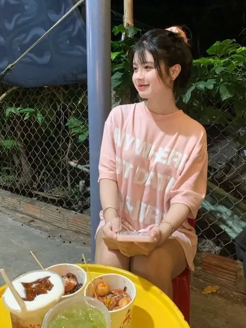 Cô nàng ngồi bên bậu cửa sổ mặc váy hoa nhí pastel, mái tóc xõa nhẹ che một bên vai, mắt long lanh nhìn ra xa với nụ cười mỉm tinh nghịch trong ánh nắng vàng dịu.