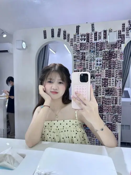 Ảnh gái đang quay mặt nghiêng nhìn hoa anh đào rơi, mặc áo len mỏng hồng nhạt, tóc dài xõa vai, ánh mắt mơ màng đầy nữ tính.