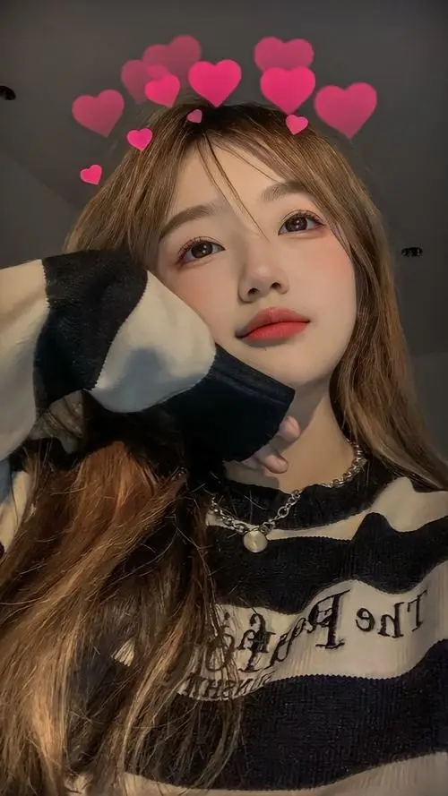 Em đang quay lưng nhẹ nhìn qua vai trong công viên mùa thu, áo khoác denim mỏng, tóc xõa dài bay nhẹ, biểu cảm ngây thơ đầy nữ tính.